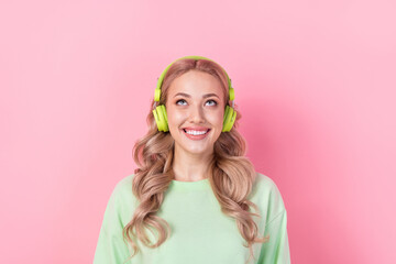 Portrait of nice millennial girl blonde curls listen earphones dreaming looking above her head...