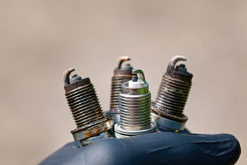 Spark plugs in hand of auto mechanic. Mechanic holding three old copper spark plugs and new one....