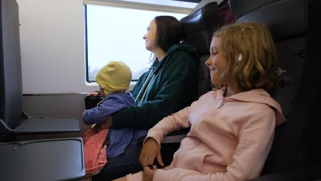 Young Caucasian mother with two kids enjoying train journey, transportation and travel concept