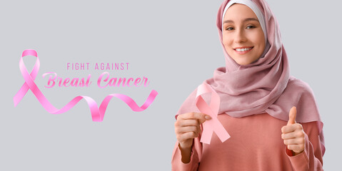 Muslim woman with pink ribbon on grey background. Breast cancer awareness