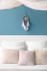 Dream catcher hanging on blue wall in bedroom