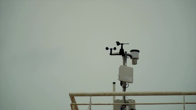 Slow motion, small weather station on the roof of a building, against cloudy sky