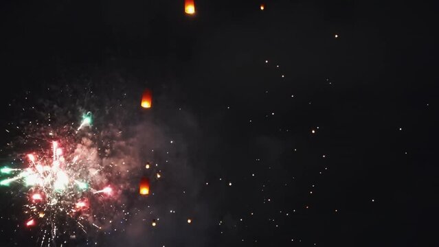 Real fireworks and paper lanterns background. abstract blur of real golden shining fireworks with bokeh lights in night sky. glowing fireworks show. New year's eve fireworks celebration. Celebration
