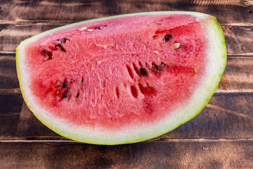 A large piece of juicy watermelon on a wood background. Slice of watermelon on a cutting board