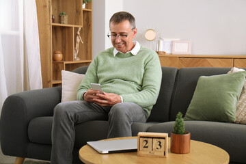 Mature man with mobile phone messaging at home