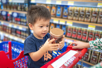 Multiracial toddler in shopping trolley in grocery store - 644187891