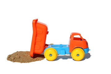 Toy plastic truck unloads construction sand on a white isolated background.