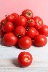 A bunch of red ripe tomatoes lie on a wooden table.