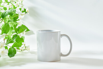 White mug mockup on a white background with sunlight and shadows of jasmine leaf flowers