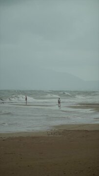  Slow motion, stormy weather in the beach, a couple on the background in the sea.