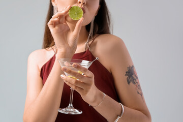 Beautiful woman with martini and lime on light background, closeup