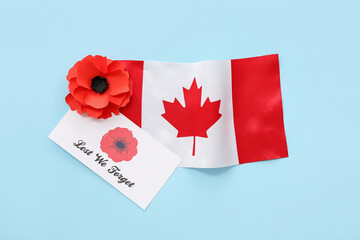 Poppy flowers, flag of Canada and card with text LEST WE FORGET on blue background. Remembrance Day