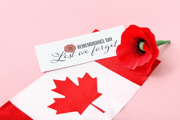 Poppy flower, flag of Canada and card with text LEST WE FORGET on pink background. Remembrance Day