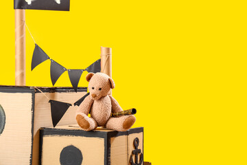 Pirate cardboard ship with toy bear on yellow background