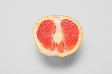 Half of fresh grapefruit with liquid on light grey background, closeup. Sex education concept