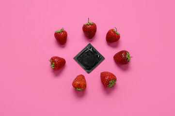 Composition with fresh strawberry and condom on pink background. Sex education concept