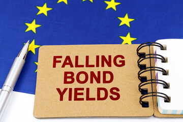 On the flag of the European Union lies a pen and a notepad with the inscription - falling bond yields