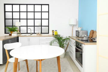 Interior of stylish kitchen with dining table and counters