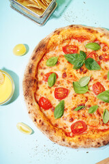 Tasty pizza Margarita with tomatoes and basil on blue table
