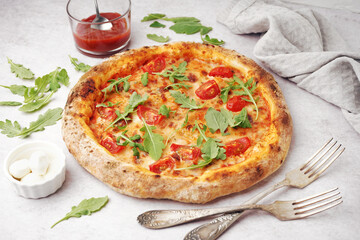 Tasty pizza Margarita with arugula and bowl of mozzarella on white table