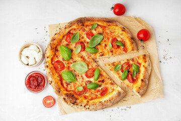 Baking paper with tasty pizza Margarita and basil on white background