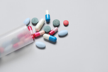 Jar with different scattered pills on grey background