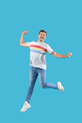 Fototapeta na wymiar Happy jumping young man on blue background