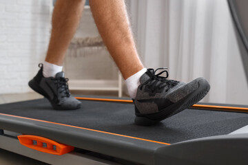 Sporty young man training on treadmill at home, closeup