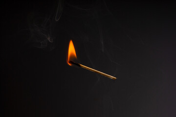 Lit falling match on a black background.