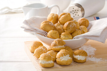 choux dough or cream puff pastries or eclair with cream and vanilla fillings on white plate - obrazy, fototapety, plakaty