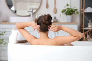 Obraz na płótnie Canvas Young woman taking bath at home, back view
