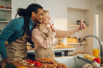 A happy multicultural couple is having a video call while cooking a meal.