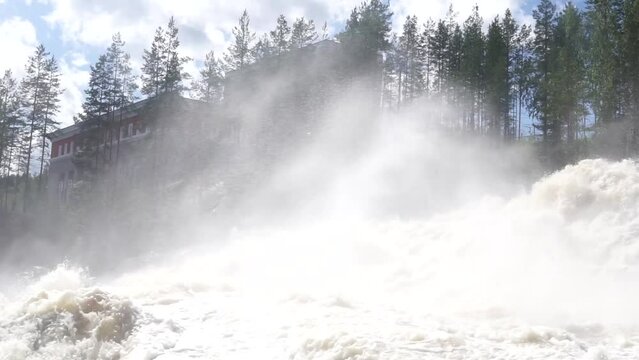 powerful stream during an idle discharge of water against the background of a building of a small hydroelectric power station