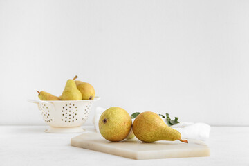 Board with ripe pears on white background