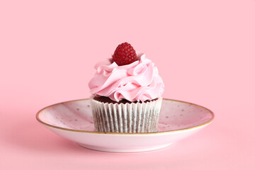 Plate with tasty raspberry cupcake on pink background