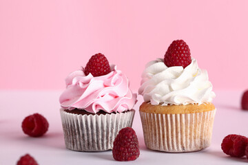 Tasty raspberry cupcakes and fresh berries on pink background