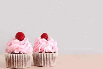 Tasty raspberry cupcakes on beige background