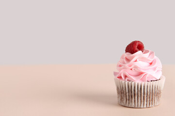 Tasty raspberry cupcake on beige background