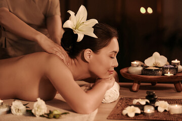 Obraz na płótnie Canvas Young woman having massage in dark spa salon
