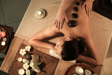 Young woman undergoing treatment with stones in dark spa salon, top view