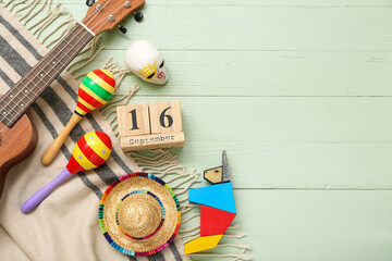 Cube calendar with date SEPTEMBER 16, maracas and Mexican decor on green wooden background. Mexico's Independence Day celebration