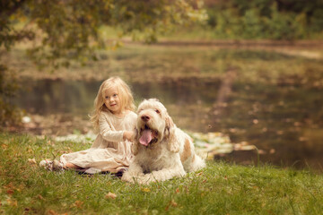 Little girl with white hair with dogs in the park in autumn