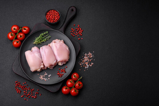 Fresh raw chicken thigh fillets with salt, spices and herbs