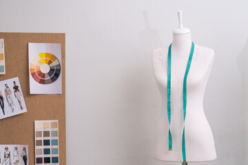 Mannequin with tape measure and board with sketches by white wall in sewing studio fashion designer for garment making in tailor workshop equipment in craft atelier