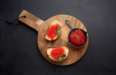 Red caviar in a black mini frying pan on the table, top view, concept of luxury and gourmet cuisine