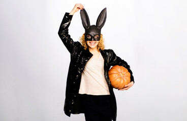 Happy Halloween. Sexy woman in black bunny mask and leather jacket with Halloween pumpkin. Smiling...