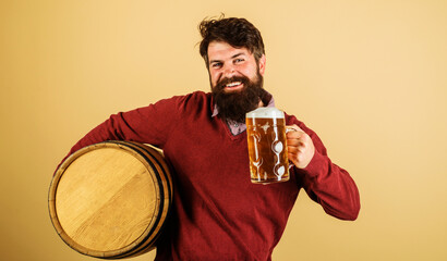 Beer time. Happy brewer with mug beer and wooden barrel. Equipment for beer preparation. Brewery...