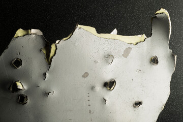 a fragment of the body shell of a downed rocket with holes close-up with texture