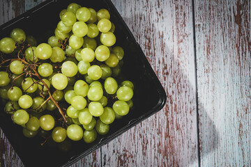 Black basket with a bunch of freshly green grapes.