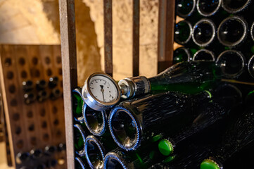 Walking in deep undergrounds caves with bottles on wooden racks, making champagne sparkling wine...